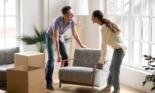 Man and woman moving a chair in their home
